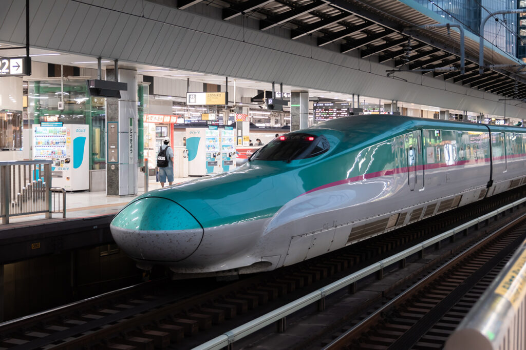 Tokyo, Japan - 10.2022: E5 Hayabusa Shinkansen waiting for passengers at Shinkansen platform at Tokyo Station with commuters and tourists waiting to board for business trip and tourism